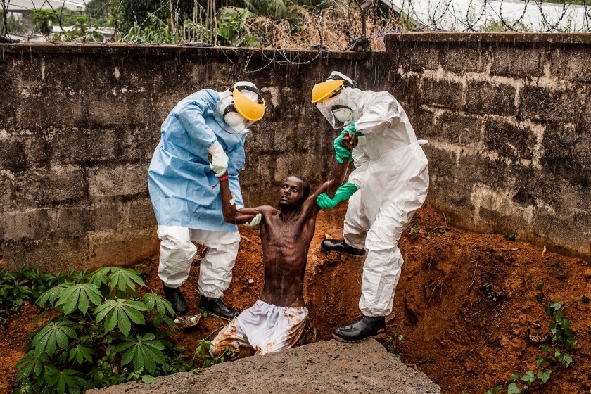 Medical staff at the Hastings Ebola Treatment Center work escort a man in the throes Ebola-induced delirium back into the isolation ward from which he escaped in Hastings, Sierra Leone on Sunday, November 23, 2014. In a state of confusion, he emerged from the isolation ward and attempted to escape over the back wall of the complex before collapsing in a convulsive state. A complete breakdown of metal facilities is a common stage of advanced Ebola. The man pictured here died shortly after this picture was taken. (Pete Muller/Prime for National Geographic)